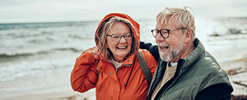 Ouder echtpaar lachen naar elkaar op het strand